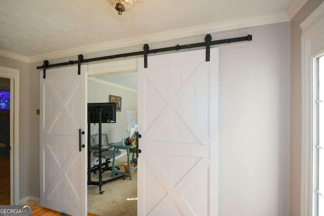 interior space featuring ornamental molding, a barn door, and a textured ceiling