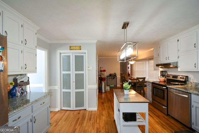 kitchen featuring hanging light fixtures, white cabinetry, appliances with stainless steel finishes, and dark stone countertops