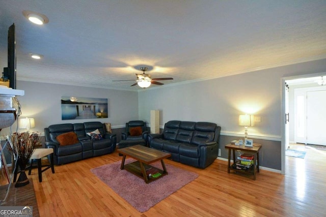 living room featuring a fireplace, ornamental molding, light hardwood / wood-style floors, and ceiling fan