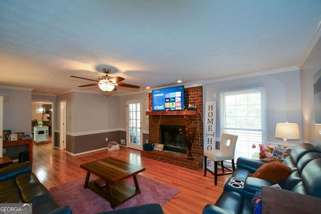 living room featuring ornamental molding, a healthy amount of sunlight, hardwood / wood-style floors, and a fireplace