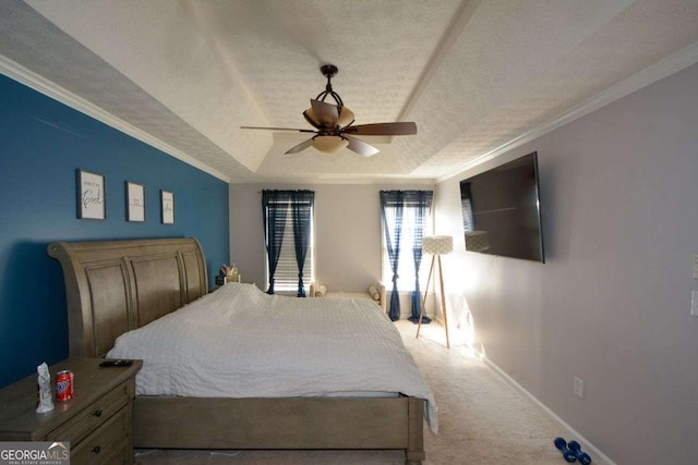 bedroom featuring a textured ceiling, ornamental molding, a tray ceiling, carpet floors, and ceiling fan