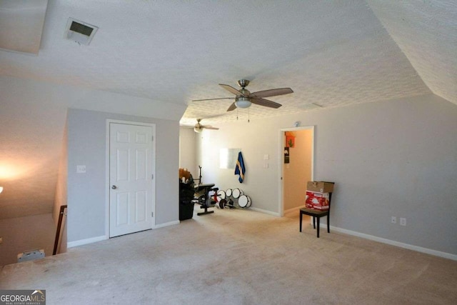 interior space featuring ceiling fan, light carpet, and a textured ceiling