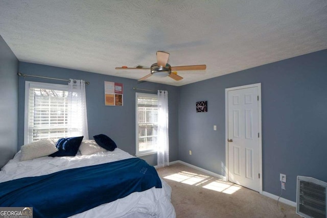 carpeted bedroom featuring ceiling fan and a textured ceiling