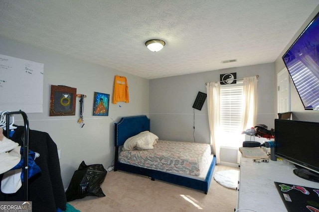 bedroom featuring light carpet and a textured ceiling