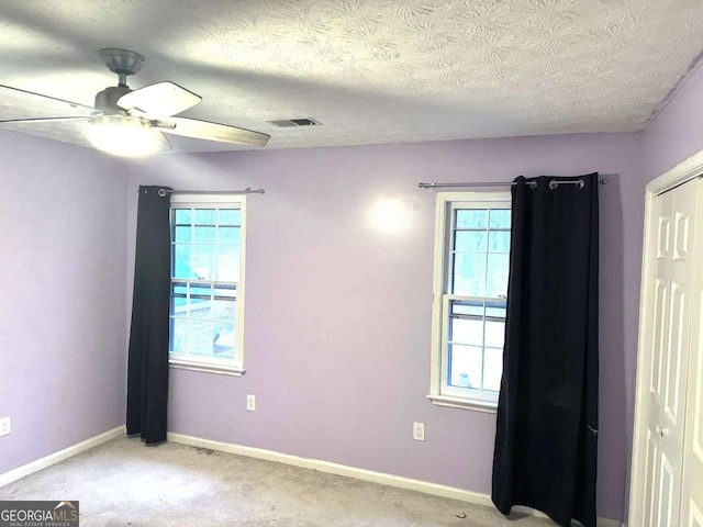 carpeted spare room featuring ceiling fan and a textured ceiling