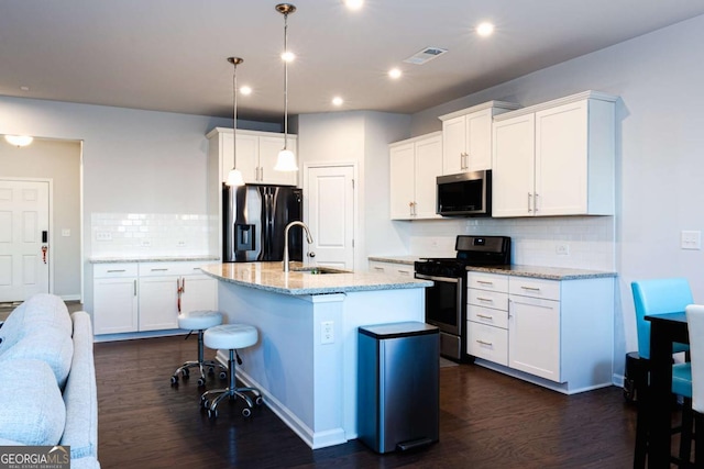 kitchen with a kitchen island with sink, hanging light fixtures, white cabinetry, and appliances with stainless steel finishes