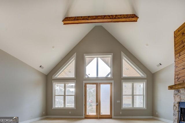 unfurnished living room featuring plenty of natural light, a fireplace, visible vents, and high vaulted ceiling