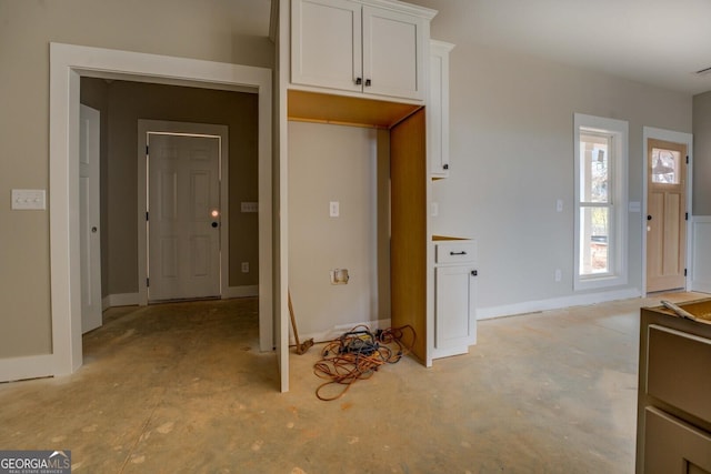 kitchen featuring white cabinets, concrete flooring, and baseboards