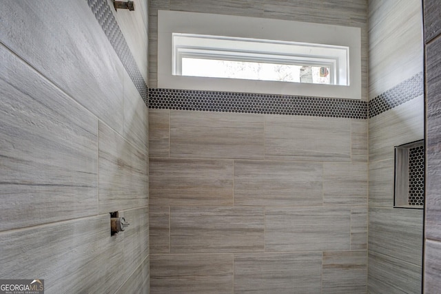 full bathroom featuring tiled shower and plenty of natural light