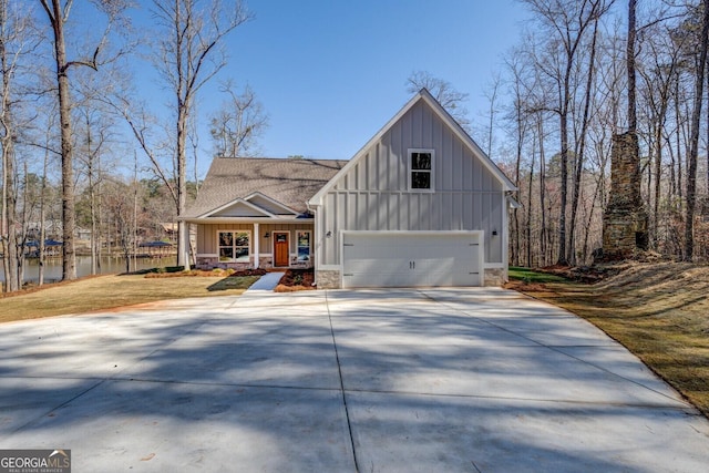 modern farmhouse featuring concrete driveway, a garage, board and batten siding, and stone siding