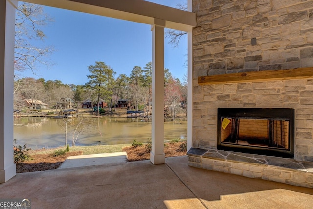 view of patio with an outdoor stone fireplace and a water view