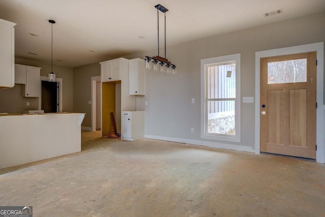 kitchen featuring visible vents, unfinished concrete flooring, pendant lighting, and white cabinets