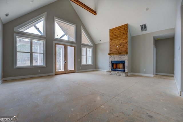 unfurnished living room with visible vents, high vaulted ceiling, a stone fireplace, and baseboards