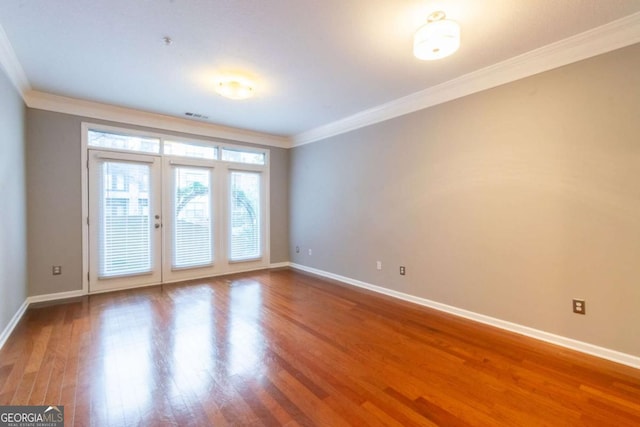 spare room featuring hardwood / wood-style floors, crown molding, and french doors