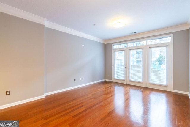 empty room with hardwood / wood-style floors and crown molding