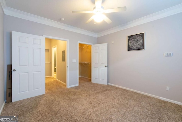 unfurnished bedroom with a walk in closet, light colored carpet, electric panel, crown molding, and a closet