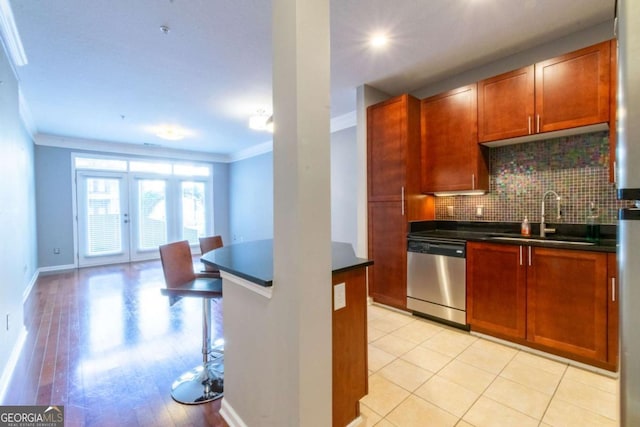 kitchen featuring sink, backsplash, ornamental molding, light tile patterned flooring, and stainless steel dishwasher