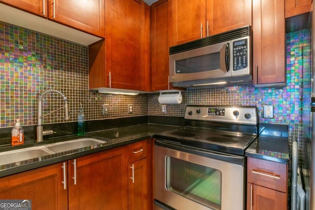 kitchen with tasteful backsplash, appliances with stainless steel finishes, sink, and dark stone countertops