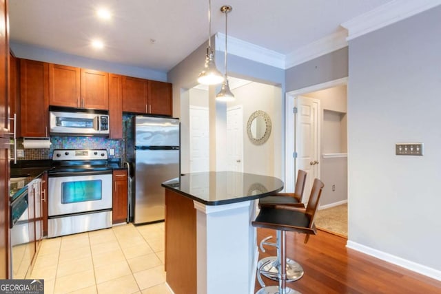 kitchen featuring backsplash, stainless steel appliances, a kitchen breakfast bar, a kitchen island, and decorative light fixtures