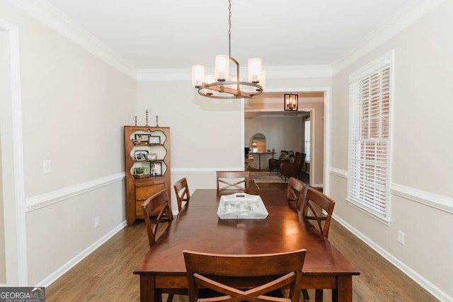 dining space featuring hardwood / wood-style flooring, crown molding, and an inviting chandelier