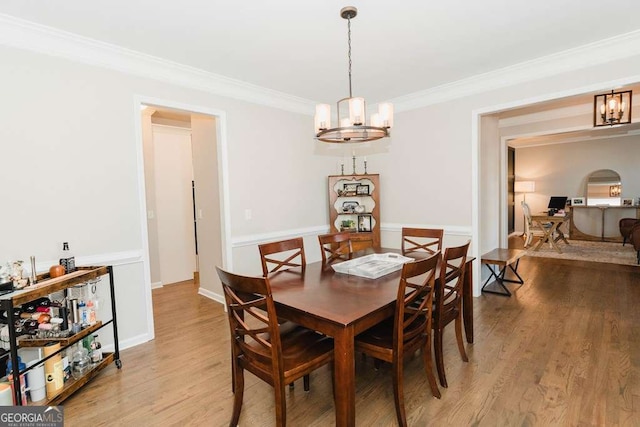 dining room featuring crown molding, wood-type flooring, and a chandelier