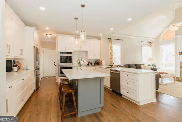 kitchen with a breakfast bar, sink, white cabinetry, a center island, and stainless steel appliances