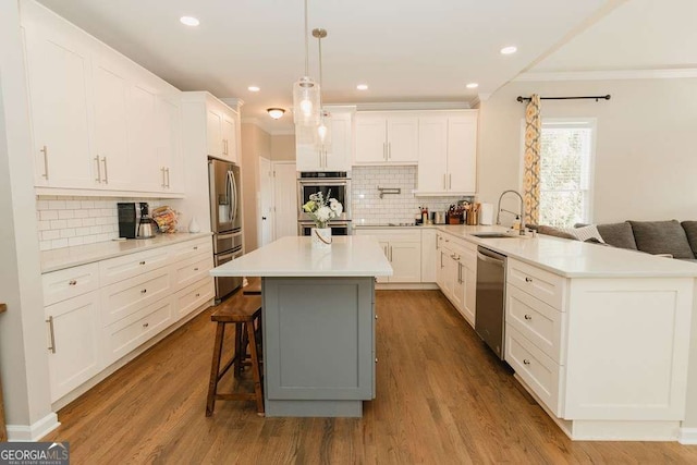 kitchen with a breakfast bar, sink, appliances with stainless steel finishes, kitchen peninsula, and white cabinets