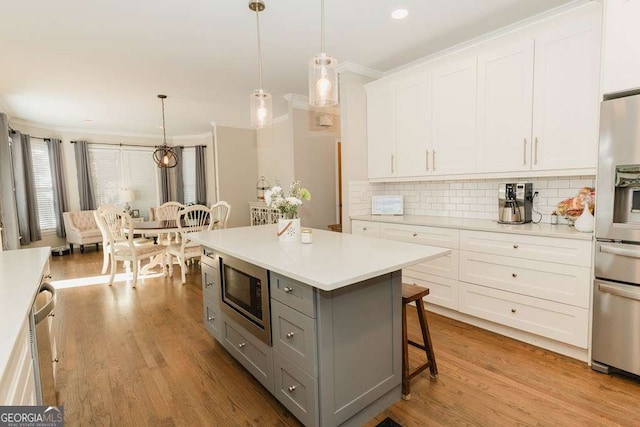 kitchen with gray cabinetry, white cabinetry, pendant lighting, and stainless steel appliances