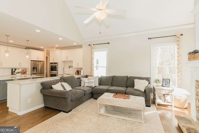 living room featuring high vaulted ceiling, sink, ceiling fan, crown molding, and light wood-type flooring