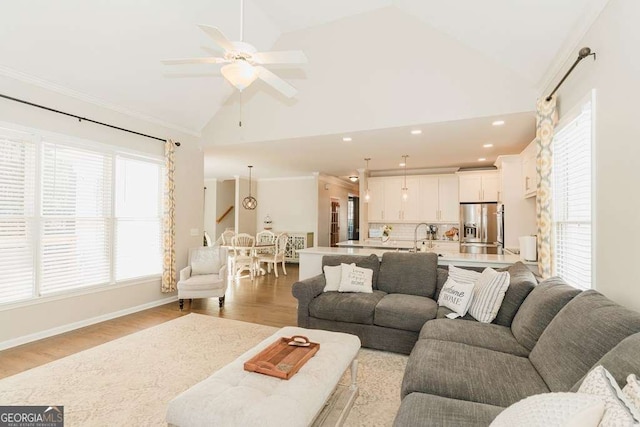 living room with crown molding, ceiling fan, high vaulted ceiling, and light hardwood / wood-style flooring