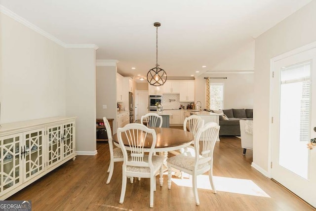 dining room featuring sink, crown molding, and light hardwood / wood-style flooring