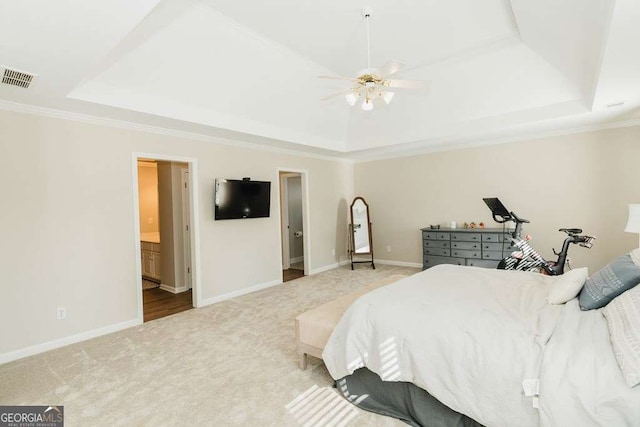 carpeted bedroom with crown molding, ceiling fan, connected bathroom, and a tray ceiling