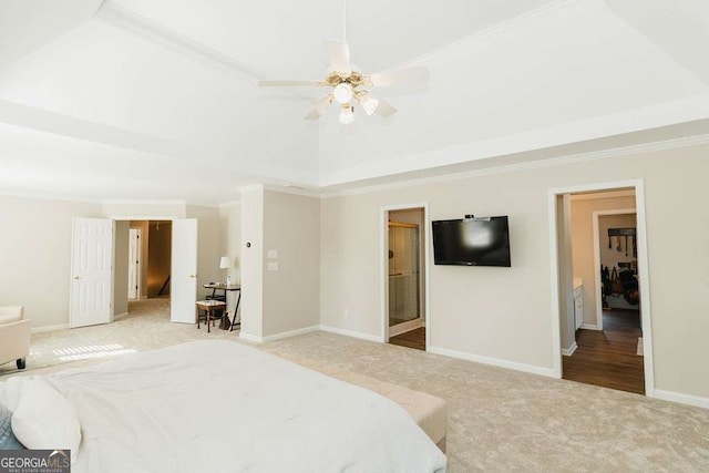 bedroom featuring crown molding, ensuite bath, ceiling fan, carpet, and a tray ceiling