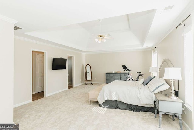 bedroom with multiple windows, crown molding, light colored carpet, and a tray ceiling