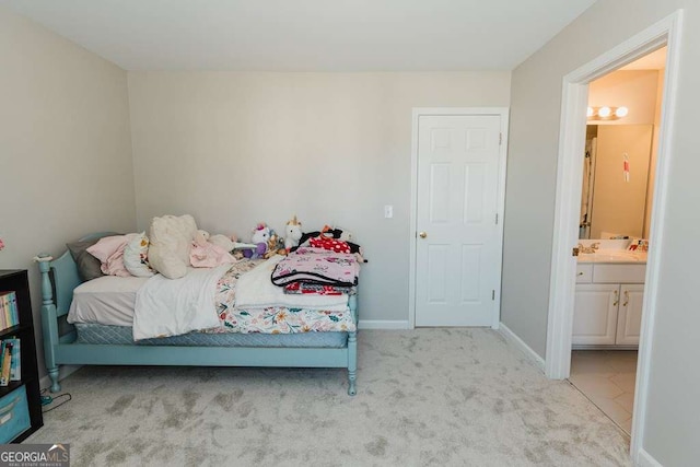 bedroom featuring ensuite bathroom, sink, and light carpet