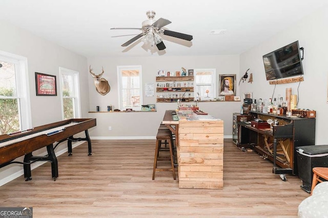 bar featuring ceiling fan, a healthy amount of sunlight, and light wood-type flooring