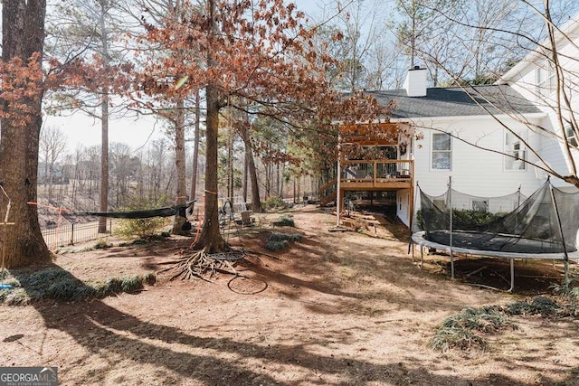 view of yard with a trampoline and a deck