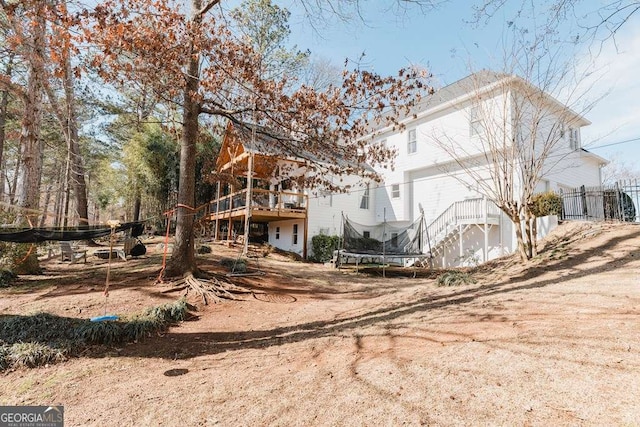 back of property featuring a wooden deck and a trampoline