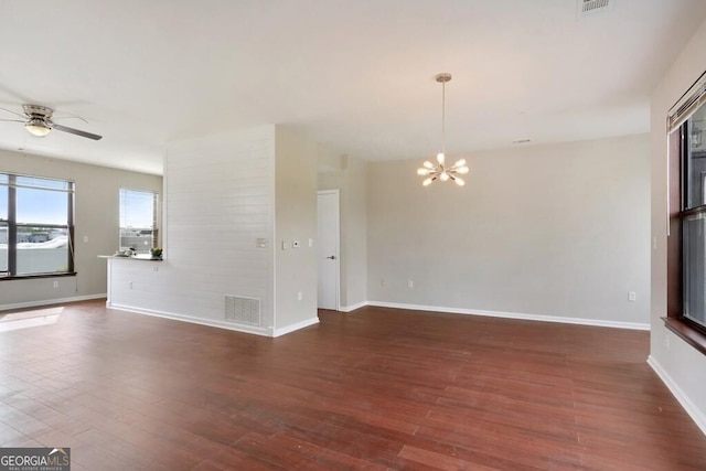 empty room featuring dark wood-type flooring and ceiling fan with notable chandelier