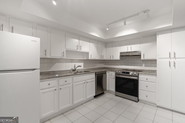 kitchen with appliances with stainless steel finishes, sink, white cabinets, dark stone counters, and a raised ceiling