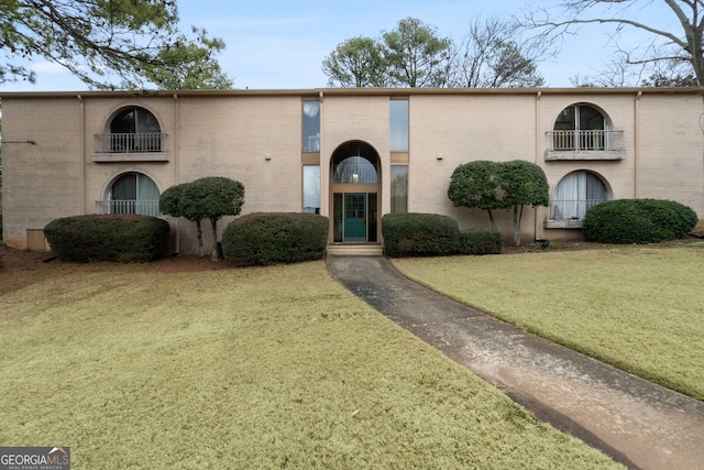 view of front of house with a balcony and a front yard