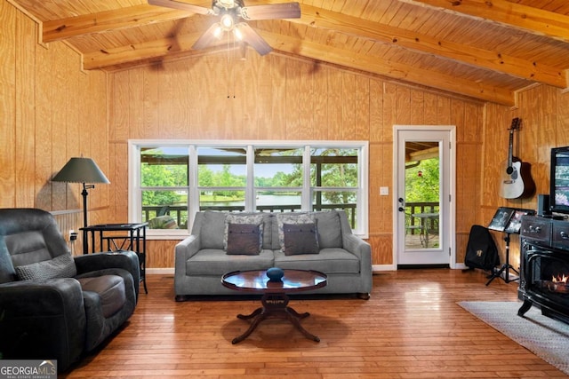 living room featuring wood ceiling, a wood stove, wooden walls, hardwood / wood-style flooring, and beam ceiling