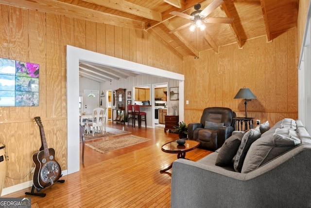 living room featuring wood-type flooring, wooden walls, and lofted ceiling with beams