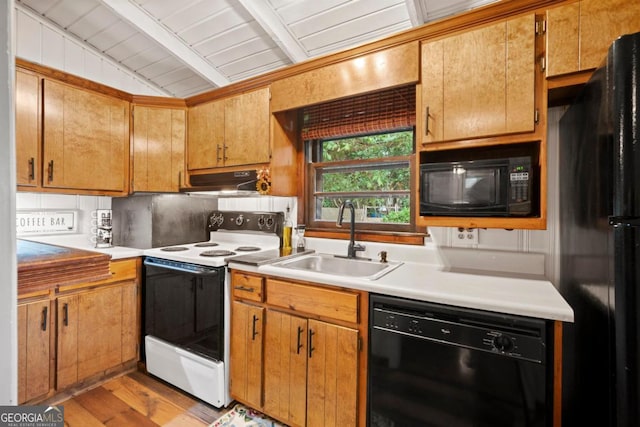 kitchen featuring sink, lofted ceiling with beams, black appliances, decorative backsplash, and light wood-type flooring