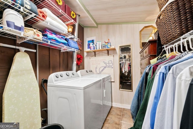 laundry area with wooden walls and washer and dryer