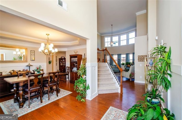 dining room featuring dark wood-type flooring, crown molding, a chandelier, and a raised ceiling