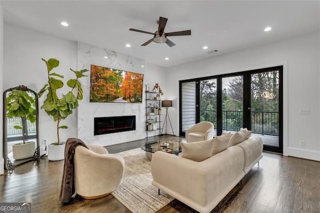 living room featuring ceiling fan, a fireplace, and dark hardwood / wood-style flooring