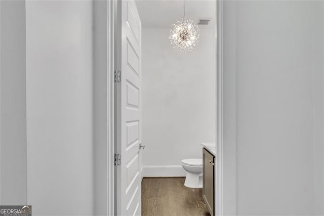 bathroom featuring vanity, toilet, a chandelier, and hardwood / wood-style floors