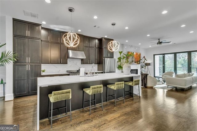 kitchen featuring a kitchen island with sink, hanging light fixtures, and a kitchen breakfast bar