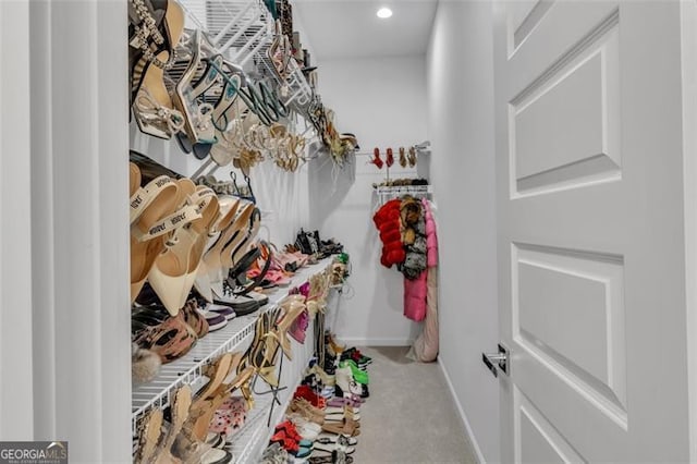 walk in closet with light carpet